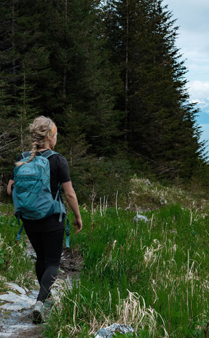 woman walking on trail with backpack